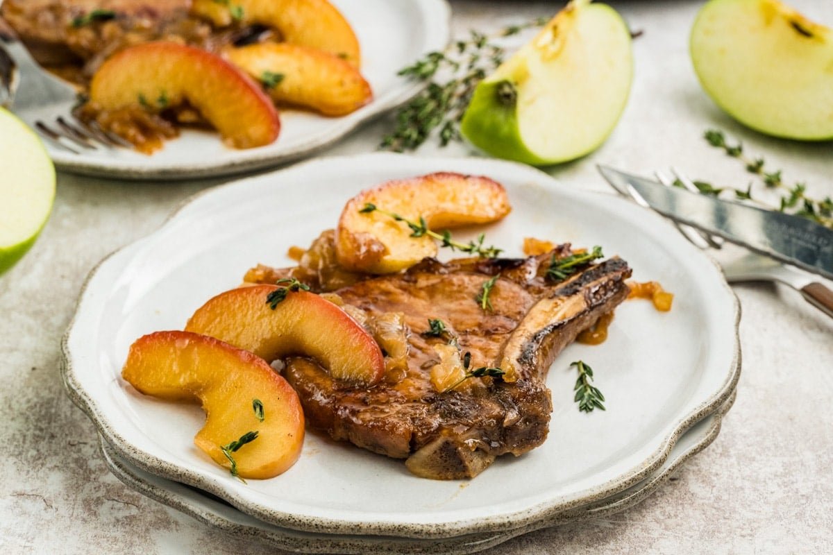 Golden roasted whole chicken dinner on a rustic wooden table with herbs and candles
